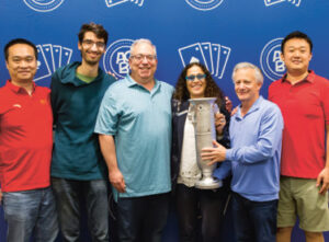 ACBL Executive Director Bronia Jenkins presents the Spingold Trophy to the 2025 winners of the Spingold Knockout Teams: Yinghao Liu, Kevin Rosenberg, Brian Platnick, captain Jeff Wolfson, Yichao Chen (Steve Garner is missing).
